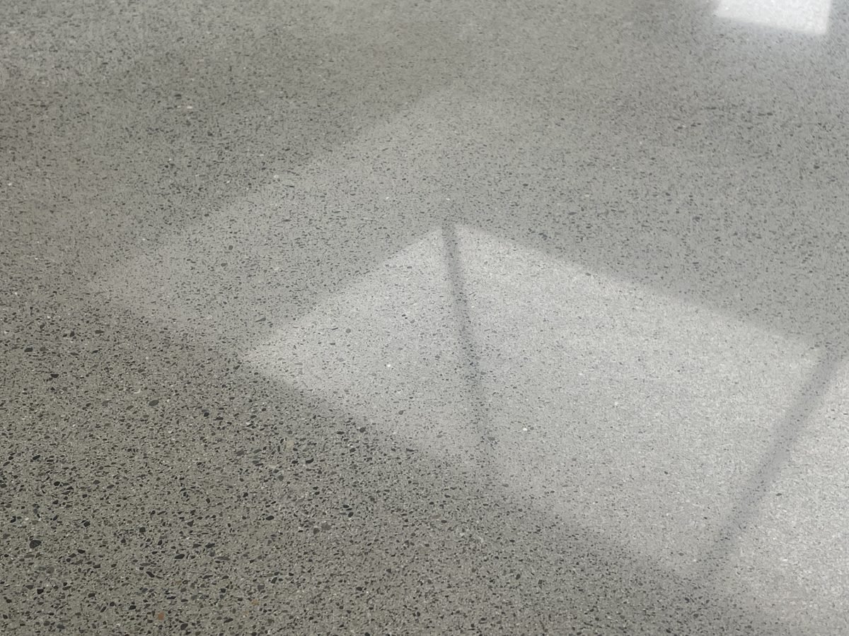 Polished concrete floor with partial aggregate exposure showing sand and small stone